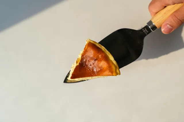 Una mano sostiene una espátula con una porción de tarta