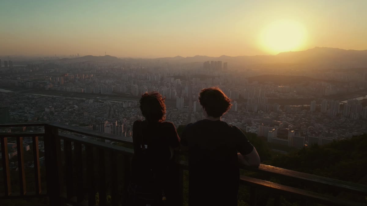 Dos figuras contemplan la ciudad al atardecer